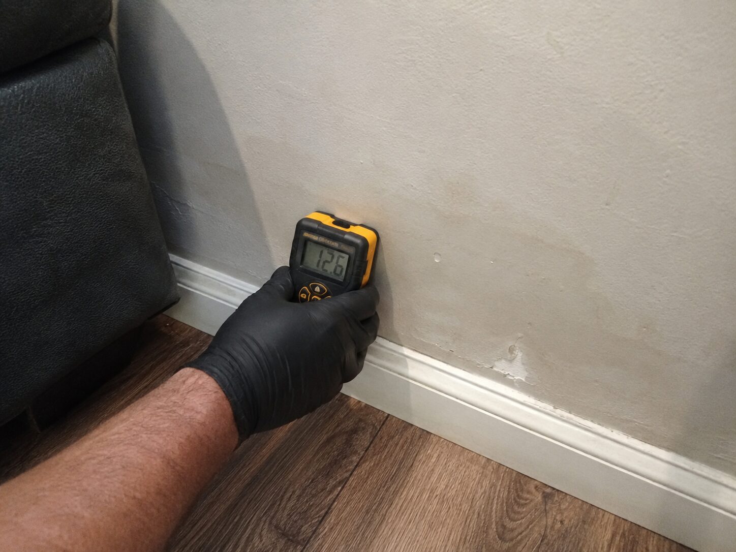 Technician using a moisture meter to check a water-damaged wall